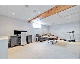 A spacious room with a couch, a chair, a desk, and a treadmill.