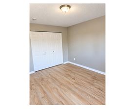 A room with a white door and wooden flooring.