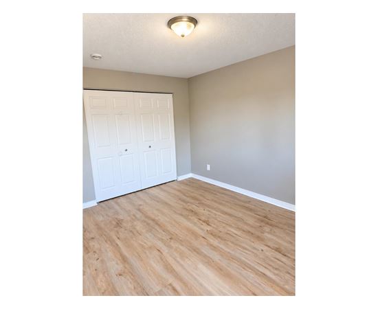 A room with a white door and wooden flooring.