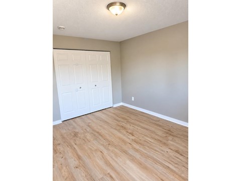 A room with a white door and wooden flooring.
