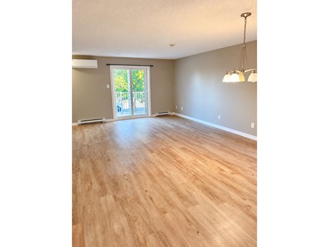 A room with wooden flooring and a sliding glass door leading outside.
