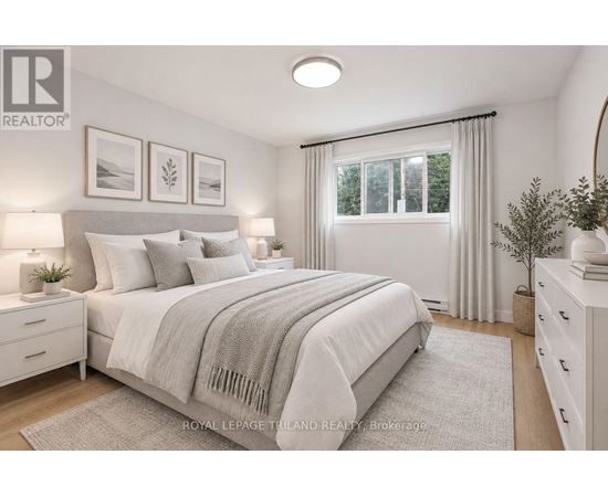 A bedroom with a large bed, a window with curtains, and a nightstand with a lamp.