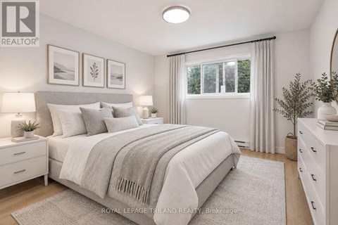 A bedroom with a large bed, a window with curtains, and a nightstand with a lamp.