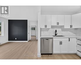 A kitchen with white cabinets and a black wall.