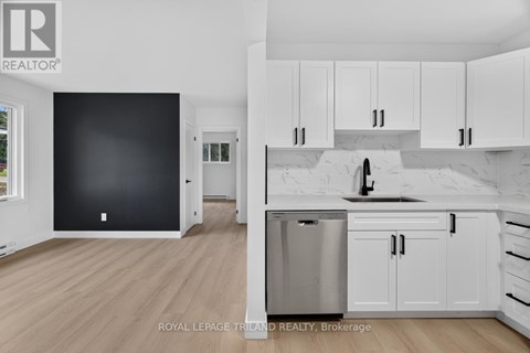 A kitchen with white cabinets and a black wall.
