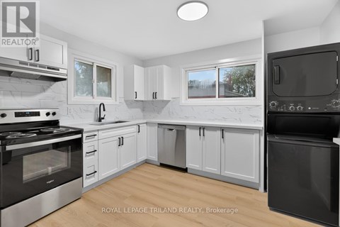 A modern kitchen with white cabinets and black appliances.