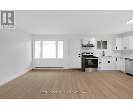 A kitchen with white cabinets and a wooden floor.
