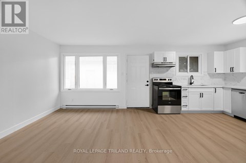 A kitchen with white cabinets and a wooden floor.
