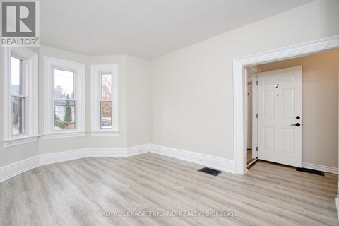 A white door is in a room with white walls and wood flooring.