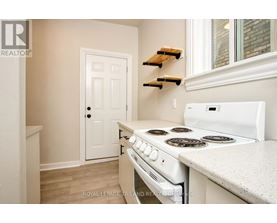 A white stove in a kitchen with a white door and white walls.