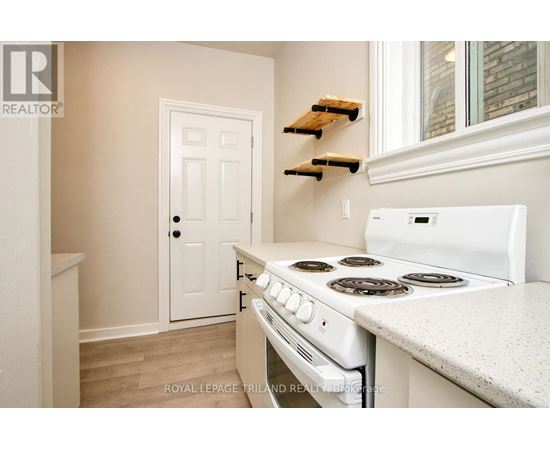 A white stove in a kitchen with a white door and white walls.