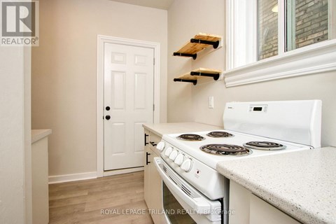 A white stove in a kitchen with a white door and white walls.