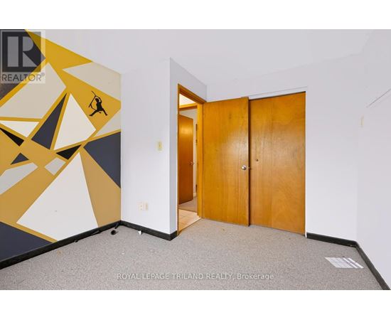 A room with a yellow and black geometric mural and a wooden door.