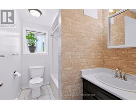 A bathroom with a toilet, sink, and mirror.