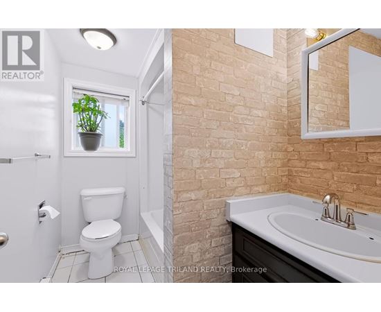 A bathroom with a toilet, sink, and mirror.