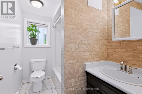 A bathroom with a toilet, sink, and mirror.
