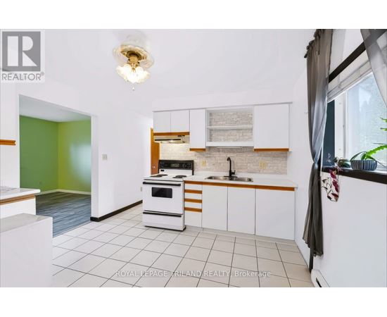 A kitchen with white cabinets and a green wall.