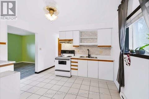 A kitchen with white cabinets and a green wall.