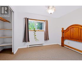 A bedroom with a bed, window, and a plant on the window sill.