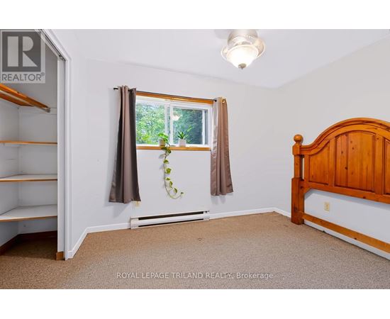 A bedroom with a bed, window, and a plant on the window sill.