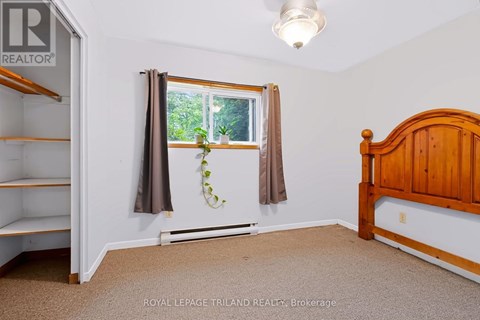 A bedroom with a bed, window, and a plant on the window sill.