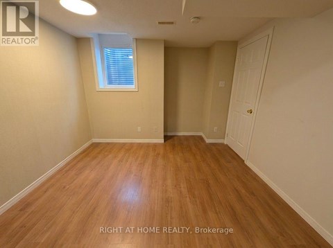 A room with wooden flooring and a window with blinds.