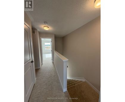 A hallway with a carpeted floor and white walls.