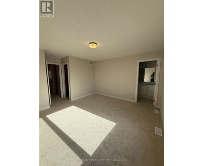 A spacious room with a carpeted floor and a ceiling light.