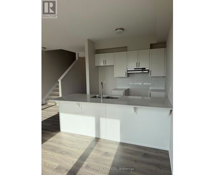 A modern kitchen with white cabinets and a wooden floor.