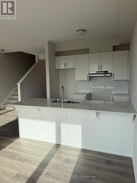 A modern kitchen with white cabinets and a wooden floor.