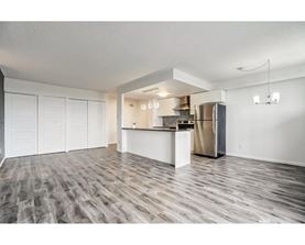 A kitchen area with a refrigerator, cabinets, and a countertop.