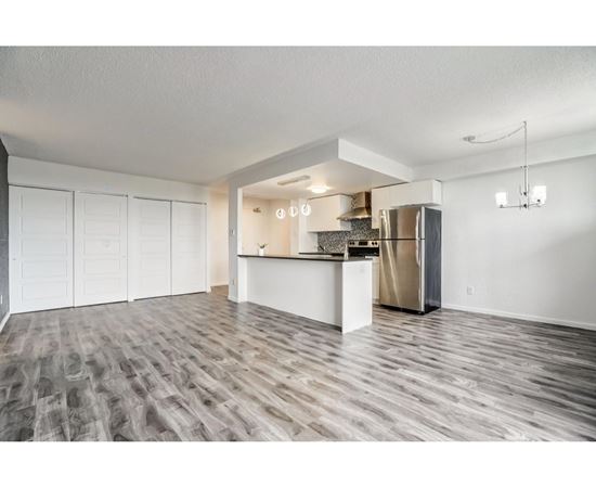 A kitchen area with a refrigerator, cabinets, and a countertop.