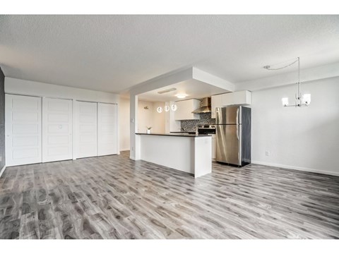 A kitchen area with a refrigerator, cabinets, and a countertop.