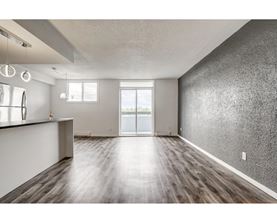 A spacious room with wooden flooring and a large window.