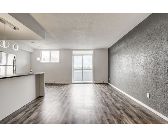 A spacious room with wooden flooring and a large window.