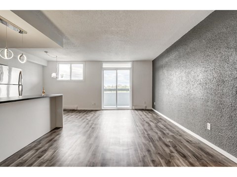 A spacious room with wooden flooring and a large window.