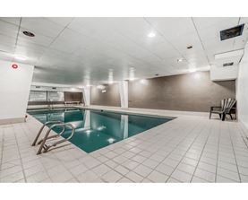 A small indoor swimming pool with a diving board.