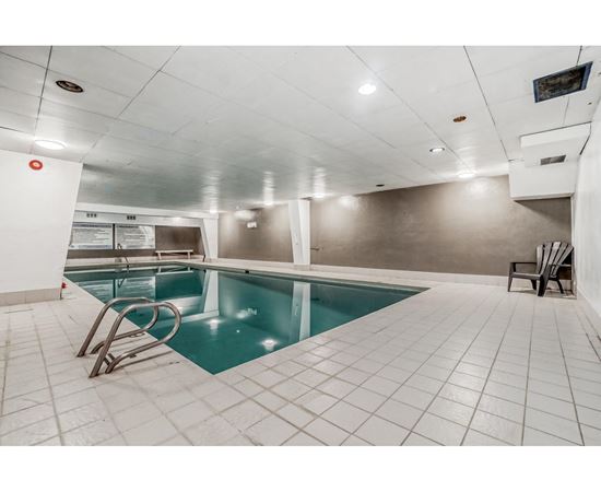 A small indoor swimming pool with a diving board.