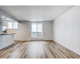 A spacious room with wooden flooring and a large window.