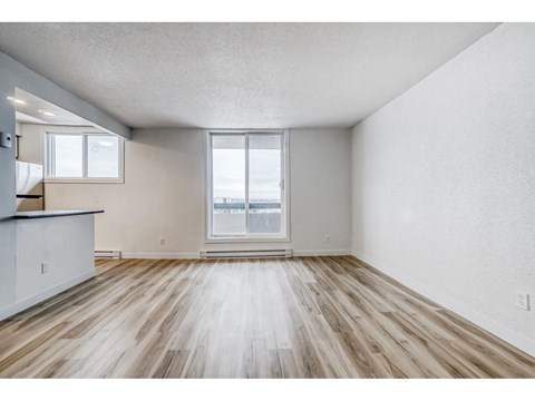 A spacious room with wooden flooring and a large window.