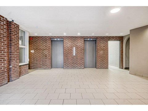 A room with brick walls and tiled floors has two doors and a window.