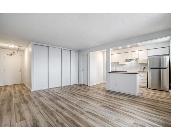 A kitchen with white cabinets and a wooden floor.