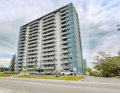 A large, modern apartment building with a parking lot in front.