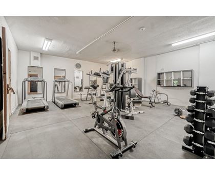 A gym with a variety of equipment including treadmills, weights, and exercise machines.