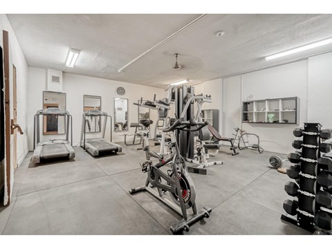 A gym with a variety of equipment including treadmills, weights, and exercise machines.