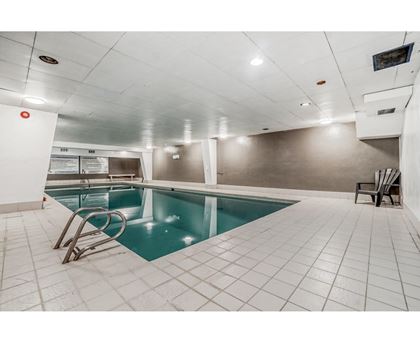 A small indoor swimming pool with a diving board.