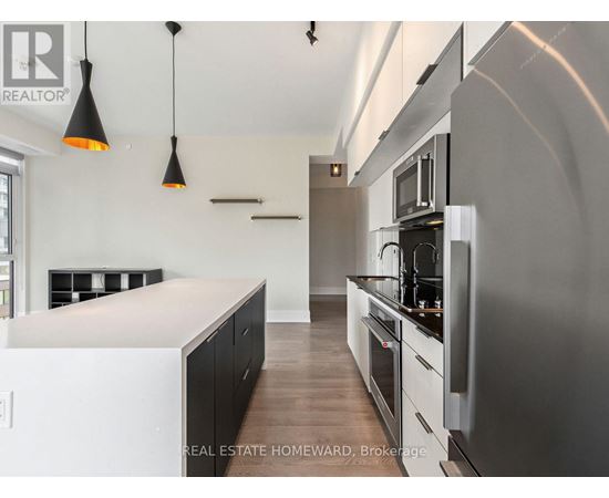 A modern kitchen with a stainless steel refrigerator and black cabinets.