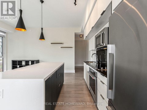 A modern kitchen with a stainless steel refrigerator and black cabinets.