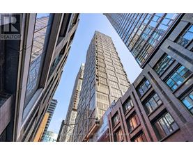 A tall building stands in the middle of a cluster of other buildings.