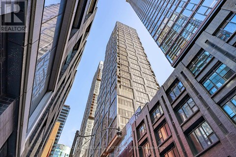 A tall building stands in the middle of a cluster of other buildings.